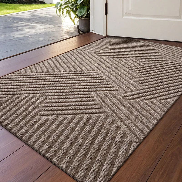 Beige 3D geometric doormat with raised groove pattern placed at indoor entrance on wooden floor.