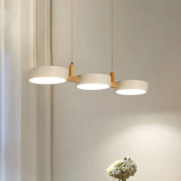 Nordic minimalist pendant light with three white cylinder shades and wooden details.