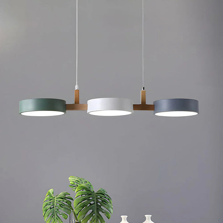 Modern Scandinavian dining room pendant light with cylinder-shaped fixtures in muted tones.