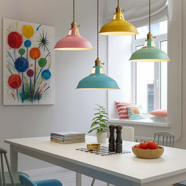Colorful pendant lights hanging above a dining table with a window and artwork in the background.