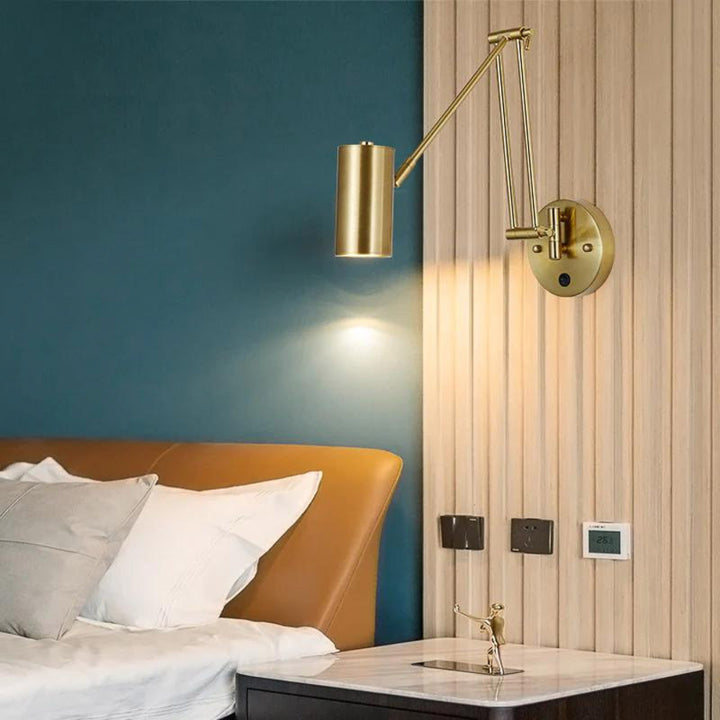 Modern Gold wall-mounted adjustable lamp in a bedroom setting with a bed and nightstand.
