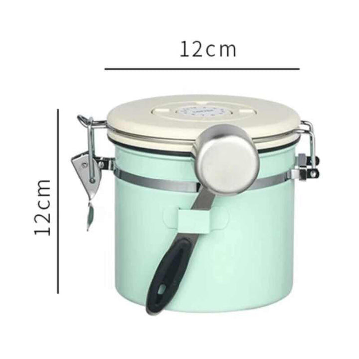 Mint green airtight coffee storage jar with cream lid and stainless steel scoop, 12 cm × 12 cm.
