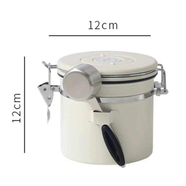 Cream airtight coffee canister with stainless steel accents and black handle, 12 cm × 12 cm.