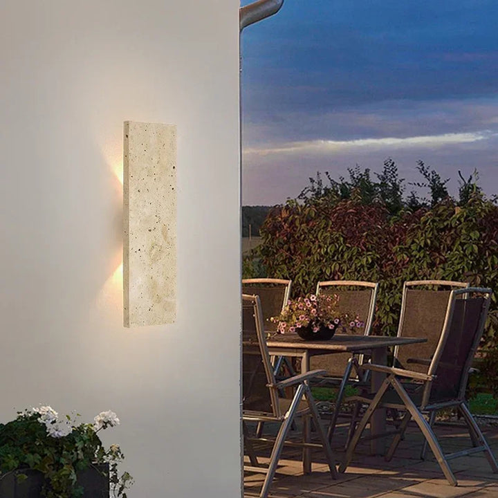 Outdoor waterproof LED wall lamp in natural stone finish, illuminating patio garden area