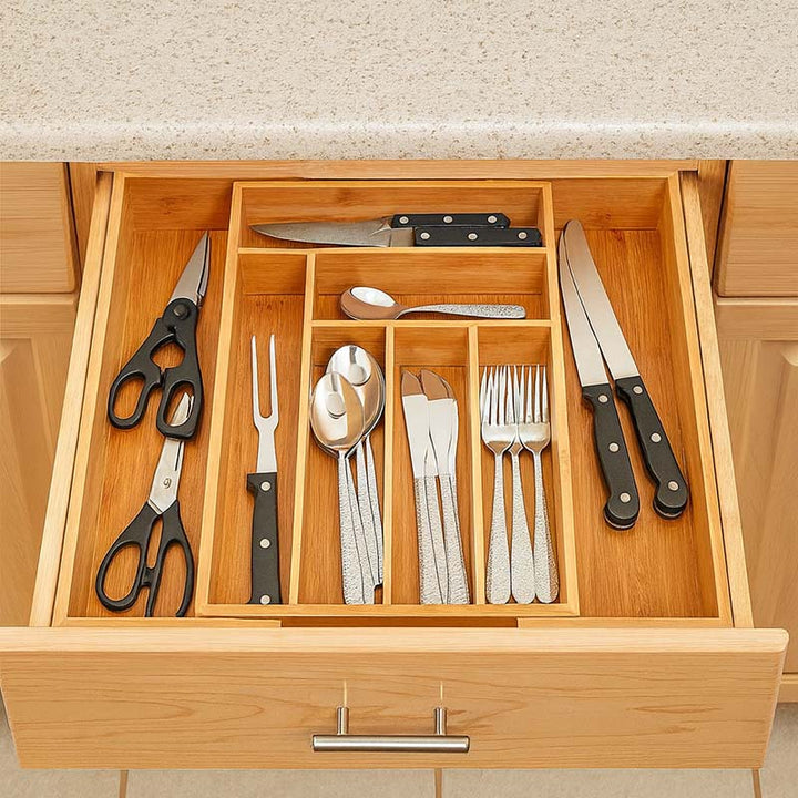 Wooden drawer organizer with cutlery including knives, forks, and spoons.