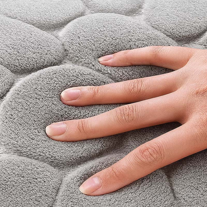 Hand touching a textured grey bath mat