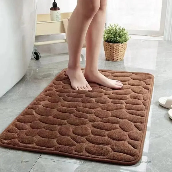 Brown textured bath mat on a bathroom floor with a person stepping onto it.