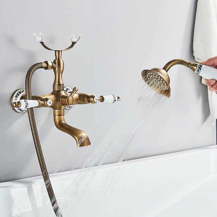 Close-up of handheld shower being used from vintage-style bathtub faucet in brushed brass finish.