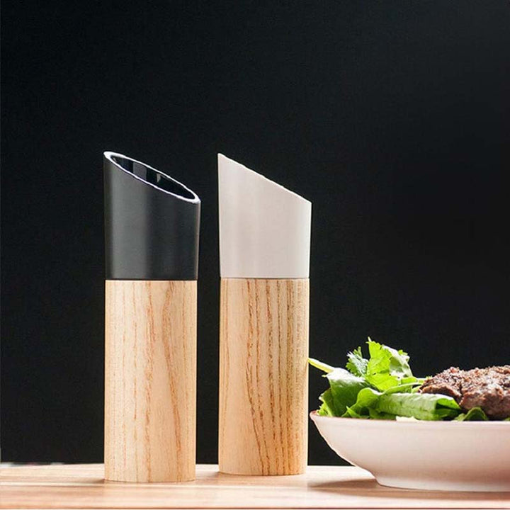 Wooden salt and pepper grinders on a wooden surface with a dark background