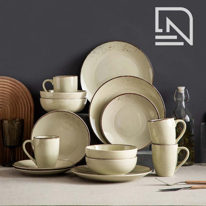 Set of ceramic dinnerware including plates, bowls, and cups on a table with a dark background.