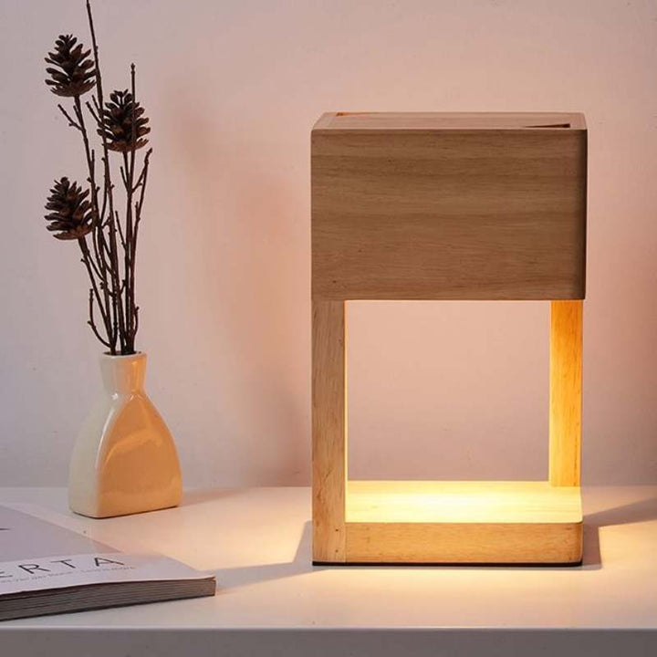 Square-frame candle warmer table lamp in natural wood, warming a jar candle; minimalist Scandinavian décor