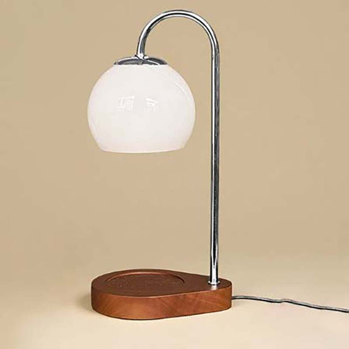 Candle warmer with white glass shade and wooden base on a beige background