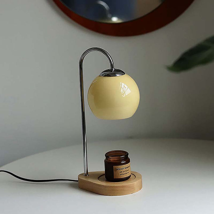 Candle warmer a round beige shade and wooden base on a white surface.