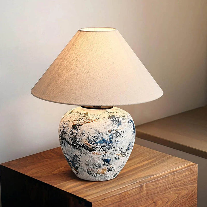 HANDLAVET ceramic handcrafted table lamp with cotton fabric shade, glowing on wooden surface