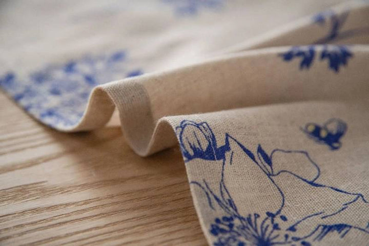 Close-up of Scandinavian cotton linen tablecloth fabric, blue floral pattern, low-maintenance material.