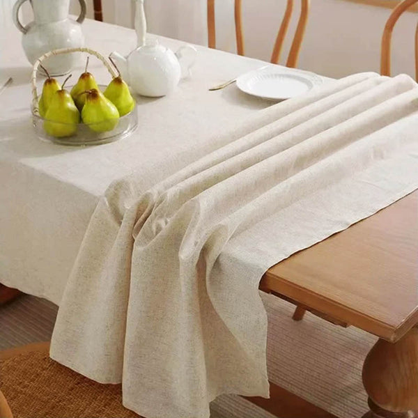 Nordic 100% cotton tablecloth in beige, draped over wooden dining table with minimalist fruit decor