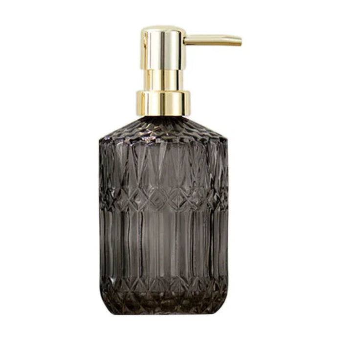 Smoky glass soap dispenser with gold pump on a white background