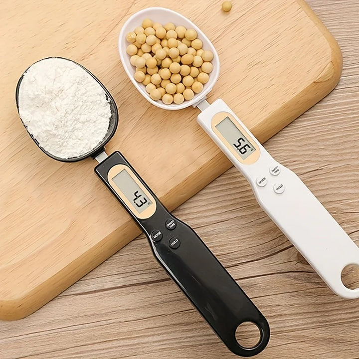 White and black digital spoon scales weighing flour and soybeans side by side on wooden board
