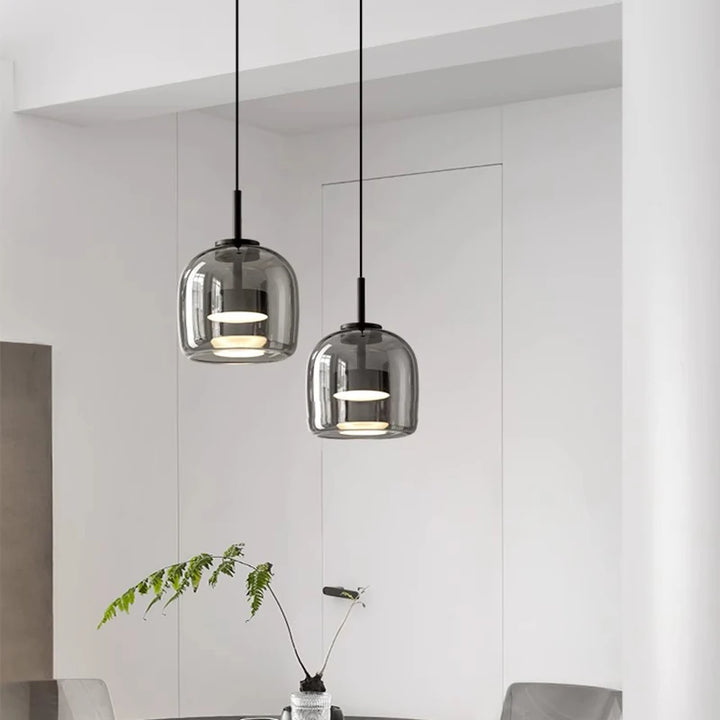Modern nordic glass pendant lights with glass shades hanging in a minimalistic room.