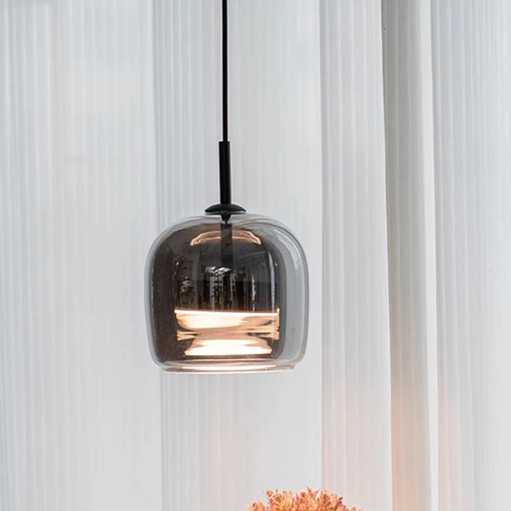 Modern pendant light with smoked glass shade against a white curtain background