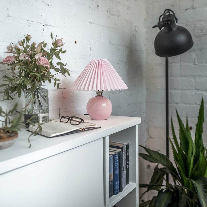 Modern pink ceramic lamp with ivory pleated shade, elegant bedside lighting for minimalist interiors.