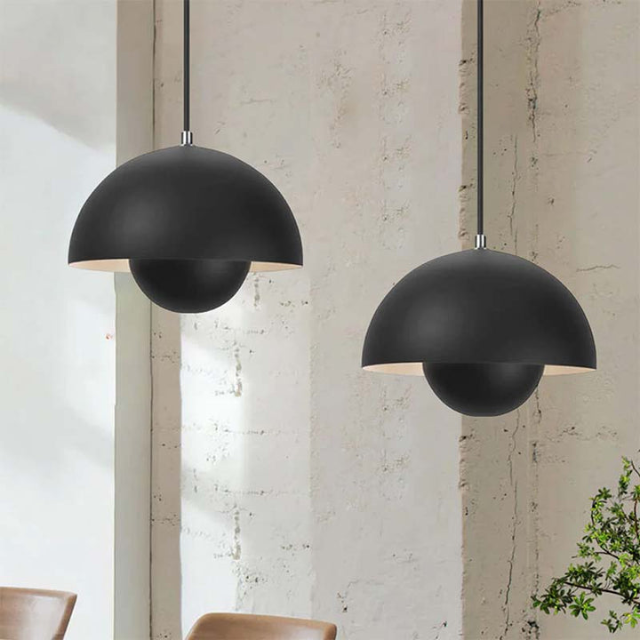 Two black pendant lights hanging against a light-colored wall.