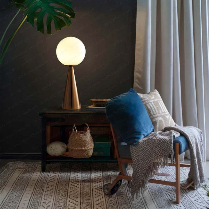 Warm globe light on brass base in Nordic corner setting, stylish ambient lamp for living or bedroom.