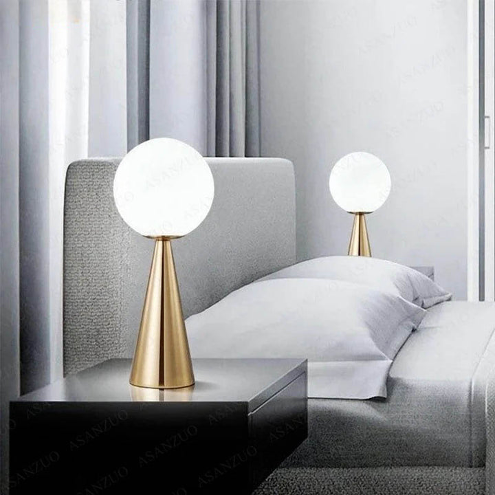 modern bedside lamp with round glass globe and brass cone base, minimal lighting for cosy bedrooms.