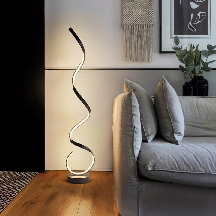 Minimalist Nordic LED floor lamp in black aluminium beside sofa, soft warm glow for living room or bedroom