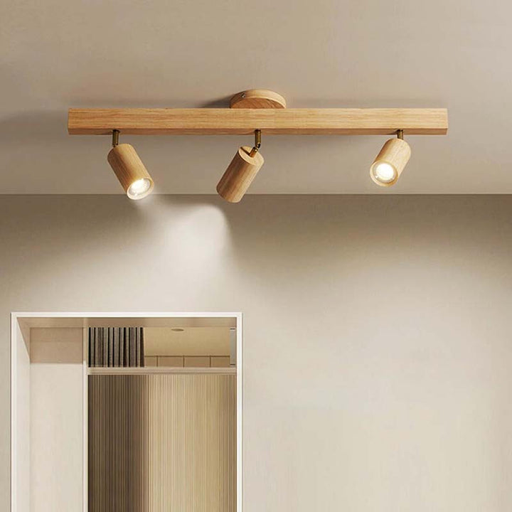 Wooden ceiling light fixture with three lights on a neutral wall.