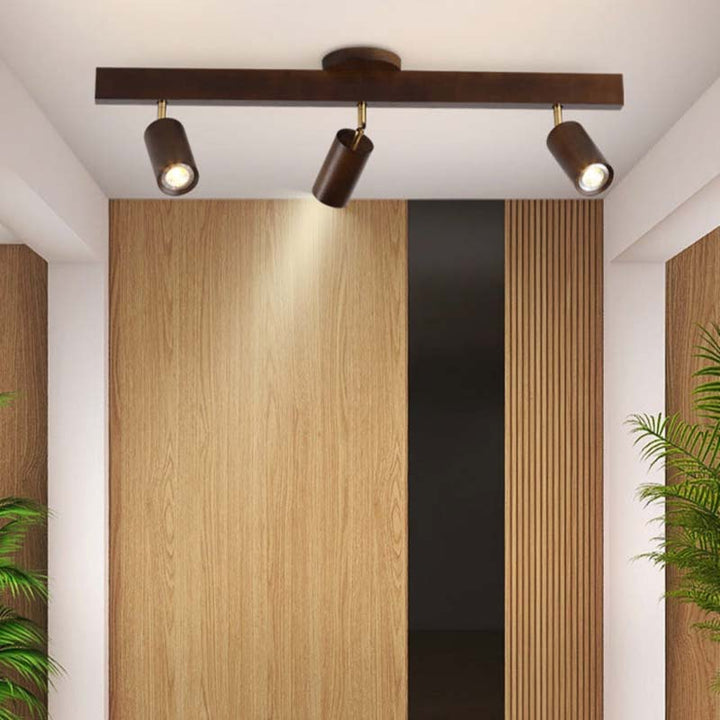 Ceiling light fixture with three lights in a room with wooden walls and plants.