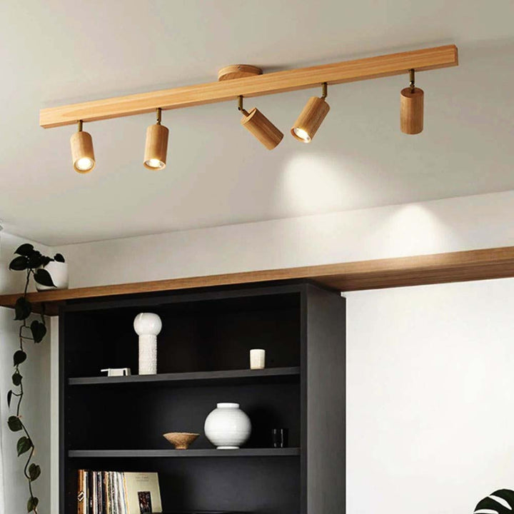 Wooden ceiling light fixture with four lights on a white wall above a shelf.
