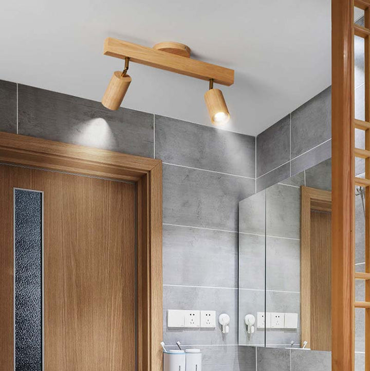 Wooden ceiling light fixture in a bathroom with gray tiled walls and wooden door.