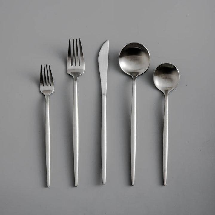 Set of silver cutlery including forks and spoons on a gray background