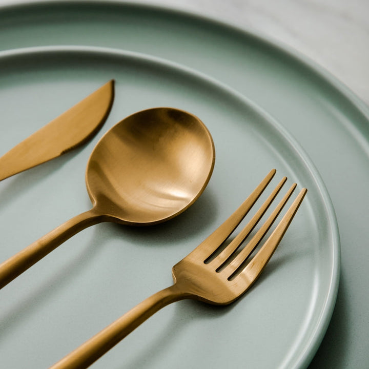 Gold spoon and fork set on a green plate