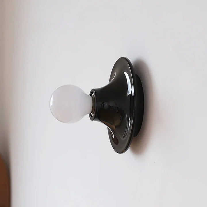 FYR wall light in glossy black finish with round base and exposed bulb decorative design