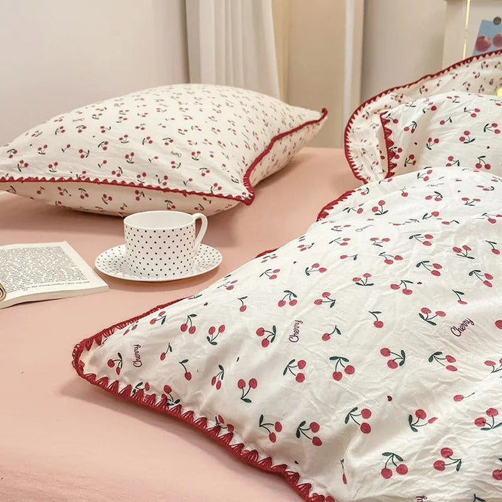 Close-up of cherry-patterned bedding with red crochet edge, showing soft texture and delicate craftsmanship