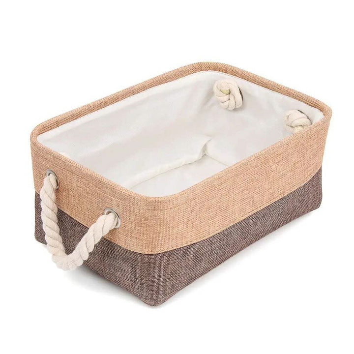 Rectangular storage basket with beige top and brown bottom, featuring rope handles on a white background.