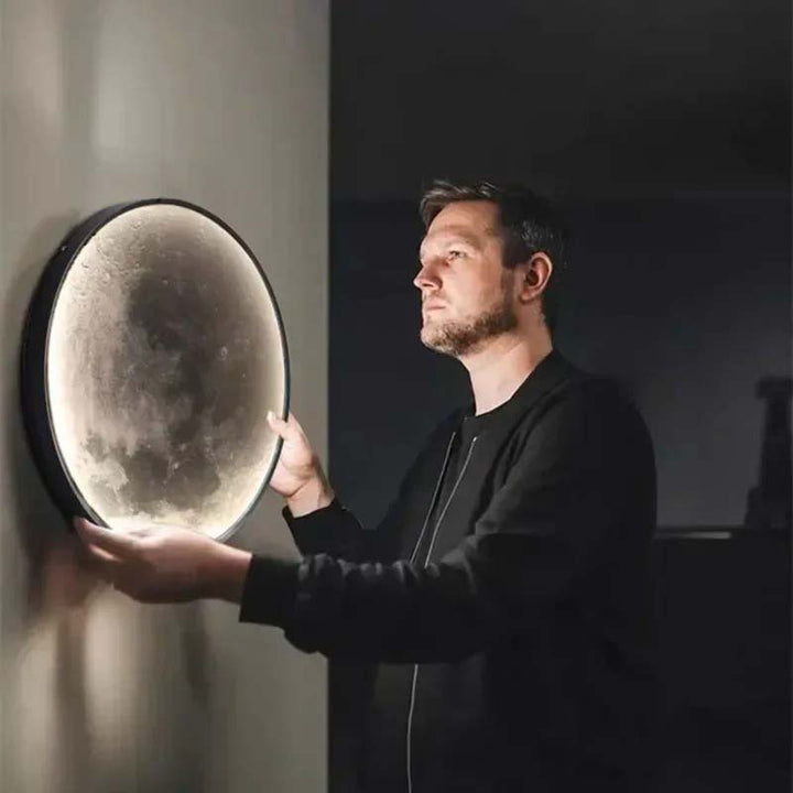 Man installing GAIA 3D Moon LED wall lamp, round dimmable light for modern home décor and soft ambient lighting