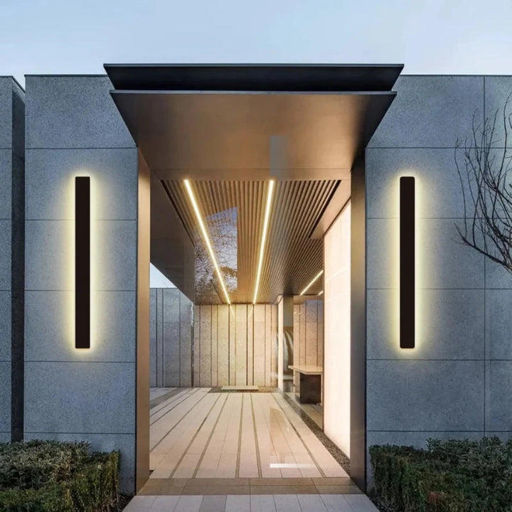 Pair of sleek black LED exterior wall lights mounted on a grey stone facade at a modern doorway