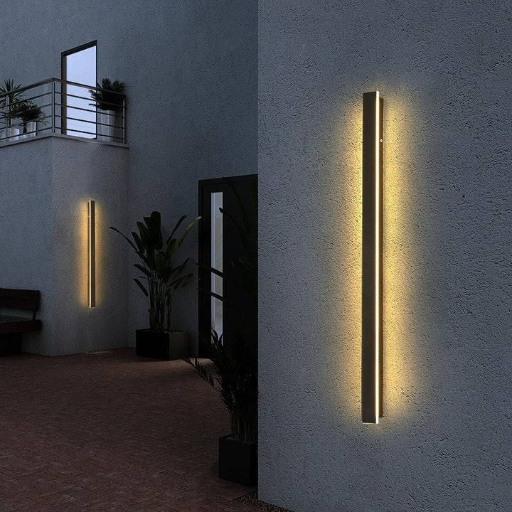 Modern vertical black LED wall lamps illuminating outdoor patio and courtyard walls at night