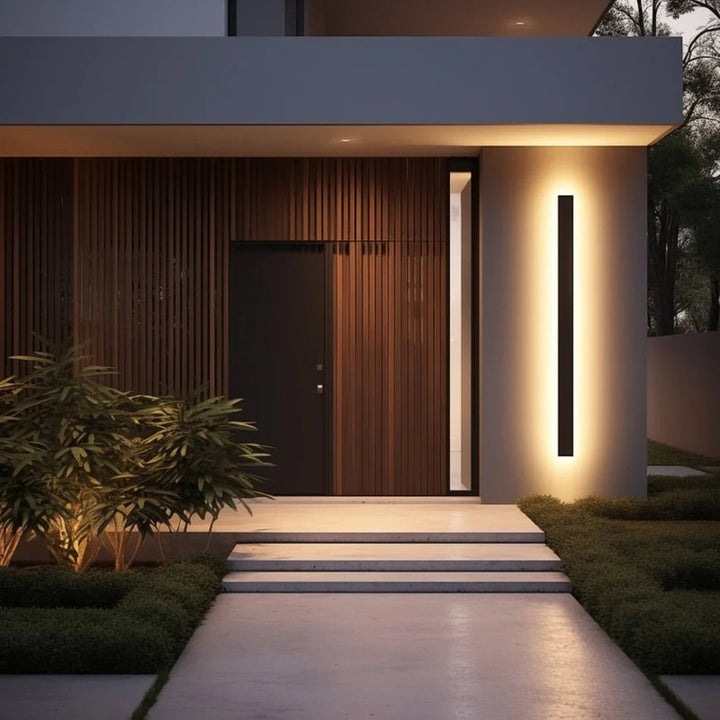 Slim black LED exterior wall lamp mounted beside the front door on the modern house facade