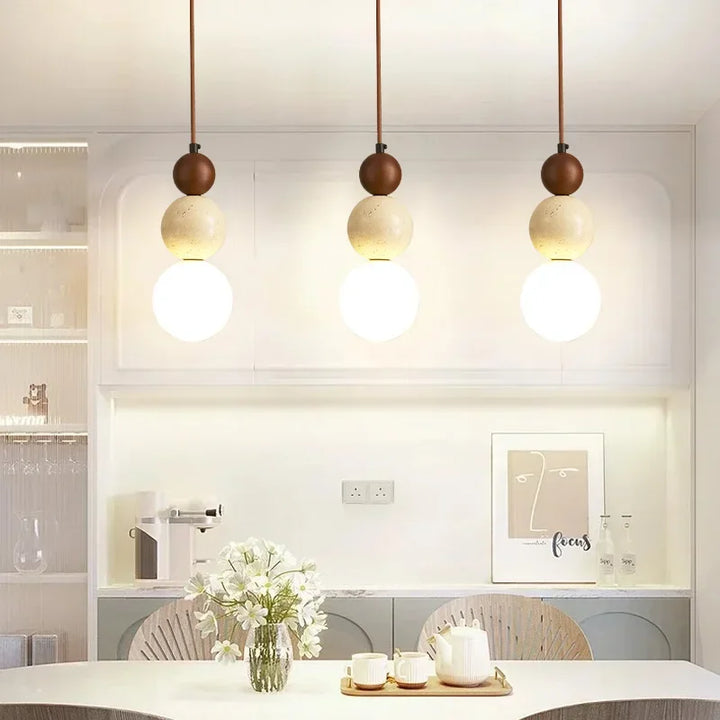 Dining room illuminated by three cream pendant lamps with elegant globe design