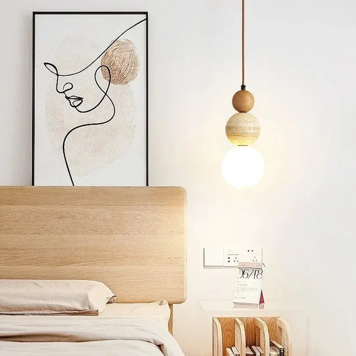 Cream globe pendant lamp with stone accent hanging beside a modern bed