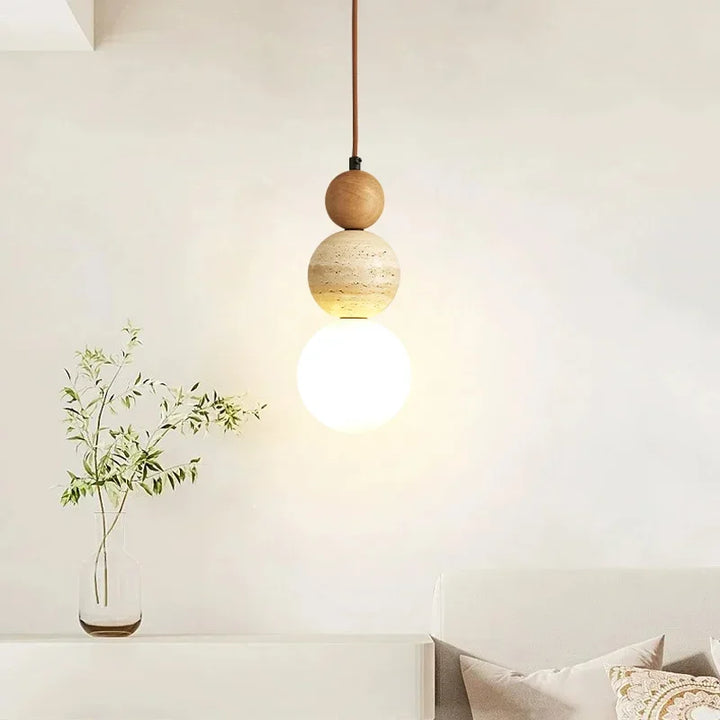 Minimalist cream pendant lamp with wood and stone accents glowing in bright room