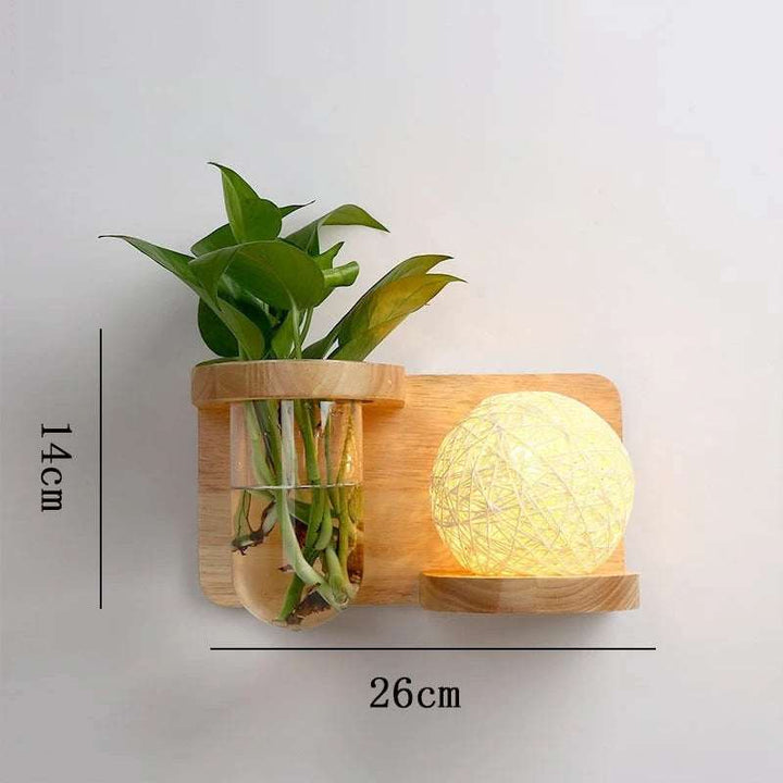 Compact wooden wall sconce with glass planter holder and woven globe LED light, 26x14cm.