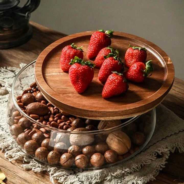 Glass and wood serving jar used as a platter for fresh strawberries and hazelnuts on a rustic table setting