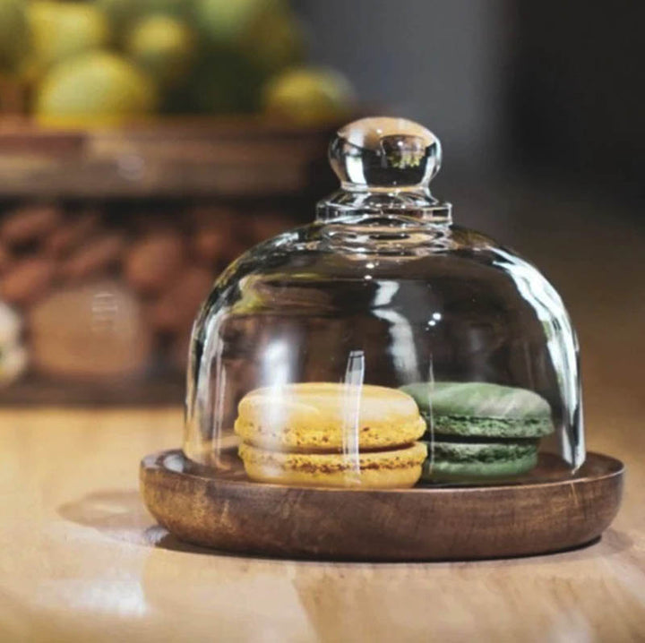 Compact glass storage dome with wooden tray and pastel macarons, ideal for countertop styling.