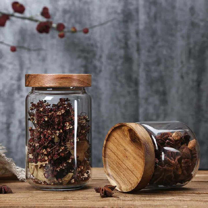 Glass jars with bamboo lids storing dried star anise and spices on wooden table
