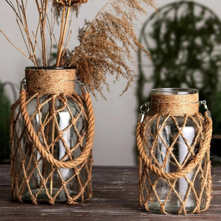 Two glass jars with rope detailing on a wooden surface, surrounded by dried plants.